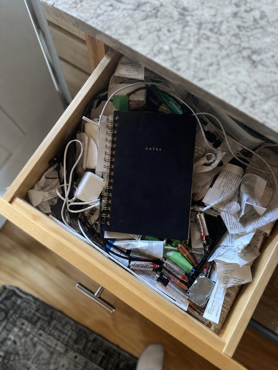 A notebook pushed into a cluttered drawer.